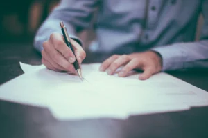 Mannlig student signerer papirer ved et skrivebord